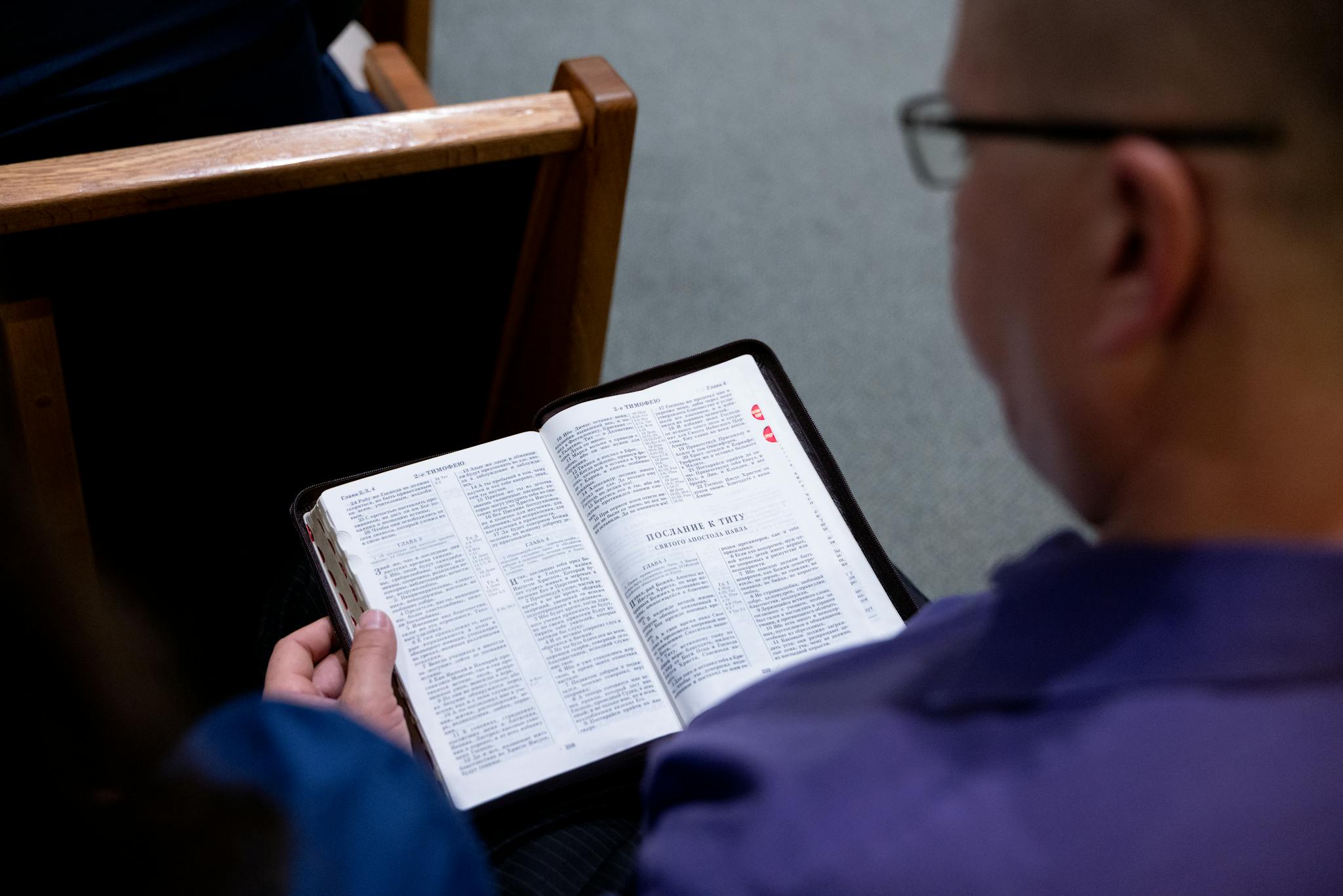 An individual studies a Bible while seated in a church. Focus on faith and reflection.